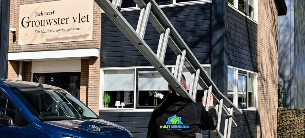 Glazenwasser in Leeuwarden heeft ladder op schouder voor een bedrijfspand
